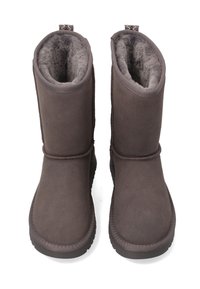 Brune ruskindsankelstøvler med blødt foer, rundet tå og tekstureret hæl. De har en løkke bagpå for nem påtagning.