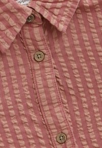 Nahaufnahme eines rosa-beige gestreiften Hemdes mit drei beigen Knöpfen und Kragendetails.