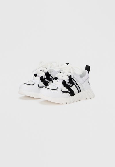 Λευκά αθλητικά παπούτσια με μαύρες λεπτομέρειες, με σχεδιασμό από δίχτυ, χοντρές κορδόνια και υφή με ανάγλυφα στοιχεία. Λαστιχένια σόλα με ρίγες της μάρκας στο πλάι.