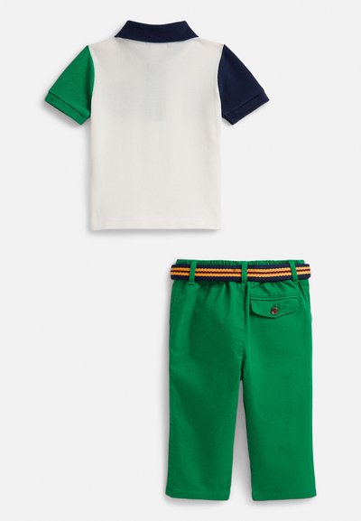 Polo majica bijele boje sa zelenim i mornarskim rukavima, uparena sa zelenim hlačama koje imaju prugasti, elastični pojas i detalj na stražnjem džepu.