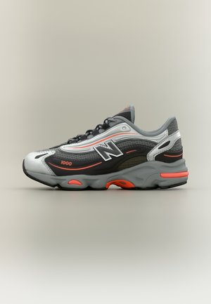 Baskets New Balance gris, noires et blanches avec des accents orange, semelle épaisse et marquage "1000" sur le côté, vues de profil.