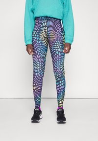 Leggings colorati con un motivo a pois in tonalità di blu, viola e colori pastello. Realizzati in un materiale elasticizzato, abbinati a sneakers nere.