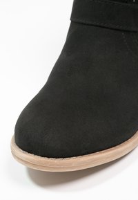 Czarne zamszowe botki za kostkę z okrągłym noskiem i minimalistycznym wzornictwem. Jasnokolorowa gumowa podeszwa z przeszyciami.