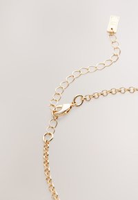 Gold chain bracelet featuring interlocking links, a lobster clasp, and an adjustable extender chain for length customization.