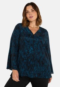 Halenka s dlouhým rukávem v modré a černé barvě s hadím vzorem, V-výstřihem, volnými rukávy a hladkou texturou. Má mírný drapérie.