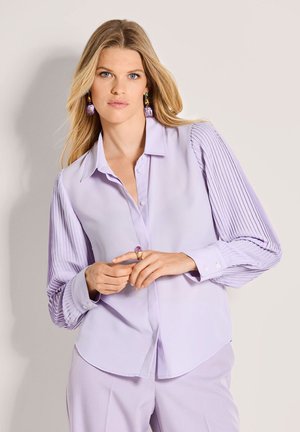 Lavendelfarbene Bluse mit glattem Oberteil und plissierten langen Ärmeln. Verfügt über einen spitzen Kragen und eine durchgehende Knopfleiste. Satinähnliche Textur, schickes Design.