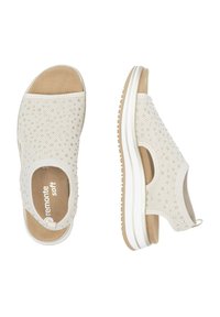 Bottines beiges à enfiler avec une tige en tissu texturé, ornées de petites décorations, semelle intérieure rembourrée et semelle en caoutchouc blanche.