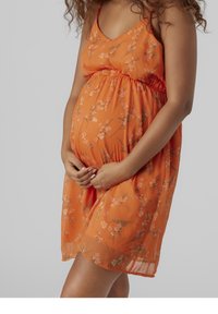 Vestido floral naranja hecho de tela ligera. Presenta una cinturilla ajustada y una falda relajada. El patrón floral incluye acentos en rosa y verde.