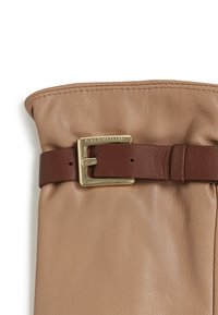 Beige lærveske med en glatt tekstur, utstyrt med en brun lærstropp og en gullfarget metallspenne. Sammenfoldet toppdesign.