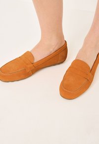 Semišové loafers v spálené oranžové barvě se designem na zashazení, zaoblenou špicí, dekorativním prošíváním a hladkým povrchem. Viditelná flexibilní gumová podešev.