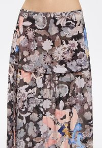 Falda con estampado floral en una suave y transparente tela. Presenta un fondo oscuro con estampados florales claros en tonos de rosa, azul y gris. Diseño con plisados.