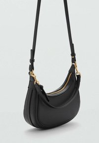 Borsa a tracolla nera in pelle con design curvo, hardware dorato, chiusura con zip e tracolla regolabile. Texture liscia, stile minimale.