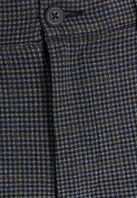 Vlněná tkanina v námořnické modři s kostkovaným vzorem. Obsahuje černý knoflík a jemnou strukturu, která ukazuje klasický střih.