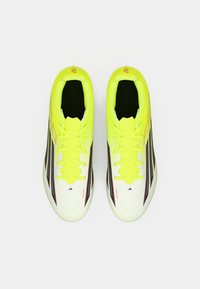 Ποδοσφαιρικά παπούτσια με λευκό και νέον κίτρινο συνθετικό επάνω μέρος, μαύρες λεπτομέρειες, στενή γραμμή και υφή επιφάνειας. Διαθέτουν κίτρινες κορδόνες.