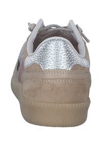 Beige sneaker with suede material, silver textured heel, pink accents, and lace detailing. The sole is translucent with a textured grip.