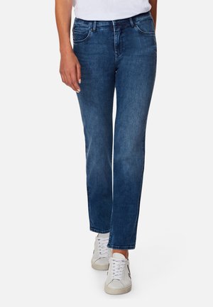 Dark blue denim jeans with a straight-leg cut, featuring front pockets and subtle stitching details, paired with white sneakers.