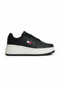Sneaker nera con finitura in pelle liscia, dotata di una suola intermedia bianca, suola esterna in gomma nera e un piccolo logo Tommy Jeans sul lato.