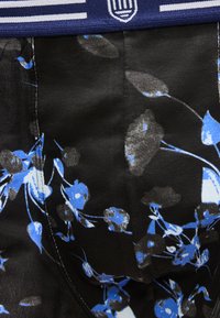 Tissu noir avec un motif floral abstrait bleu et gris, taille bleue avec des rayures blanches et un écusson.