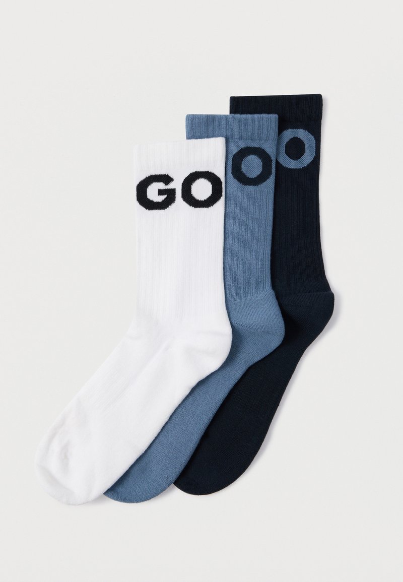 Τρία ζευγάρια κάλτσες σε λευκό, ανοιχτό μπλε και σκούρο μπλε, με ριγωτή υφή και μαύρη εκτύπωση των γραμμάτων «GO» σε κάθε κάλτσα.