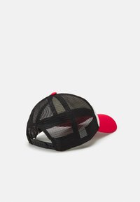 Gorra de malla negra con visera y botón frontales rojos. Cuenta con un cierre de tipo snapback y un diseño estructurado con forro interior visible.