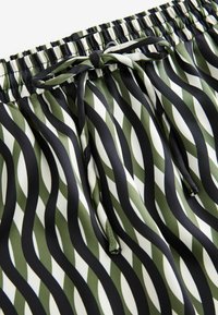 Grüne und weiße gemusterte Shorts mit wellenförmigen Streifen, elastischem Bund mit Kordelzug und glatter Textur.