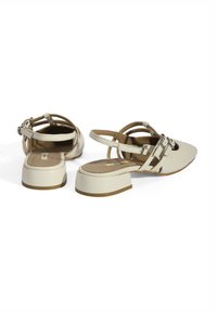 Beige slingback shoes with a pointed toe and a block heel. Constructed from smooth leather with multiple strap details and buckle accents.