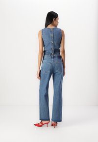 Costumul din denim include un top fără mâneci cu spatele cu nasturi, asortat cu blugi largi. Include pantofi cu toc înalt roșii cu accente negre.