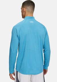 Helles blaues, langärmeliges Sportshirt mit Stehkragen und strukturiertem Stoff. Verfügt über ein Logo auf der Rückseite und eine taillierte Passform.