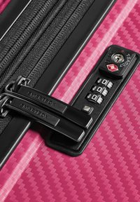 Valise rose à coque rigide avec deux tirettes de fermeture éclair noires et serrure à combinaison à trois chiffres approuvée par la TSA.