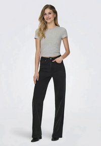 Jeans pretos de cintura alta com pernas largas, combinados com uma blusa justa de manga curta cinza claro. Tecido suave com um design clássico de cinco bolsos.