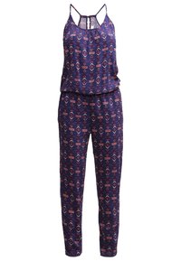 Combinaison bleu marine avec un design à motifs en triangles rouges et blancs. Présente des fines bretelles, une taille froncée et des jambes fuselées. Texture du tissu lisse.