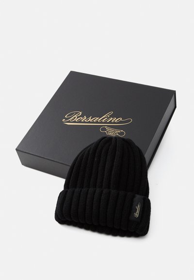 Beanie nero a coste realizzato in materiale lavorato a maglia, con risvolto e una piccola etichetta nera con scritte dorate. Presentato in una scatola nera.