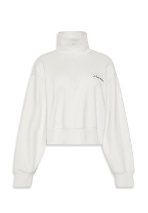 Kirptas baltas džemperis su aukštu apykakle ir priekine užtrauktuku; turi mažą žalią Calvin Klein logotipą kairėje krūtinės pusėje.