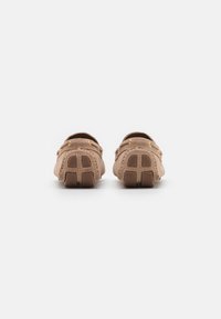 Brown suede loafers with a smooth finish, featuring decorative stitching and subtle golden hardware accents. Treaded rubber sole for grip.