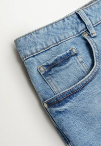 Jeans en denim bleu clair avec une petite poche arrière, des coutures visibles et un détail en métal sur la ceinture.