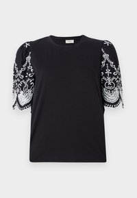 Svart bomulls t-shirt med korta puffärmar som har intrikata vita broderier och scallopade kanter, rund halsringning och en avslappnad passform.