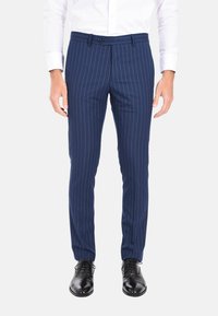 Pantaloni a righe navy realizzati in un tessuto morbido, con una vestibilità su misura, passanti per cintura e chiusura con bottone. Scarpa nera formale sotto.