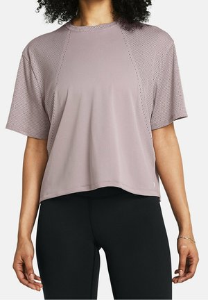 Vrouw draagt een losvallende licht mauve geperforeerde top met korte mouwen en nauwsluitende zwarte legging, zichtbaar van nek tot heupen.