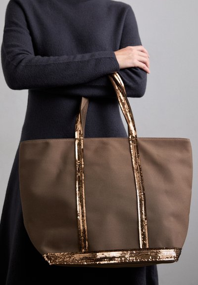 Sac fourre-tout marron avec des rayures dorées en sequins ; fabriqué en tissu durable, il présente un large corps et de longues poignées pour un transport facile.