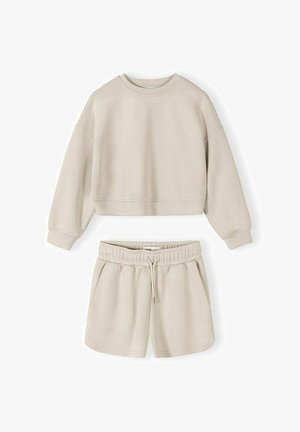 Bėgių ilgomis rankovėmis trumpintas megztinis, derinamas su bėgiojančiomis šortais su elastinga juosmeniu ir raišteliu, abu pagaminti iš minkštos medžiagos.