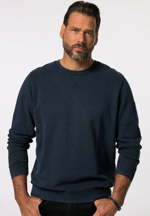 Felpa girocollo blu navy realizzata in tessuto morbido, con maniche lunghe, polsini a coste e una piccola tasca decorativa sul braccio sinistro.