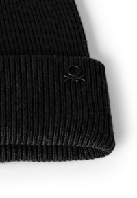 Beanie nero a coste con risvolto, caratterizzato da un piccolo logo nero. Il materiale sembra morbido con una finitura testurizzata.