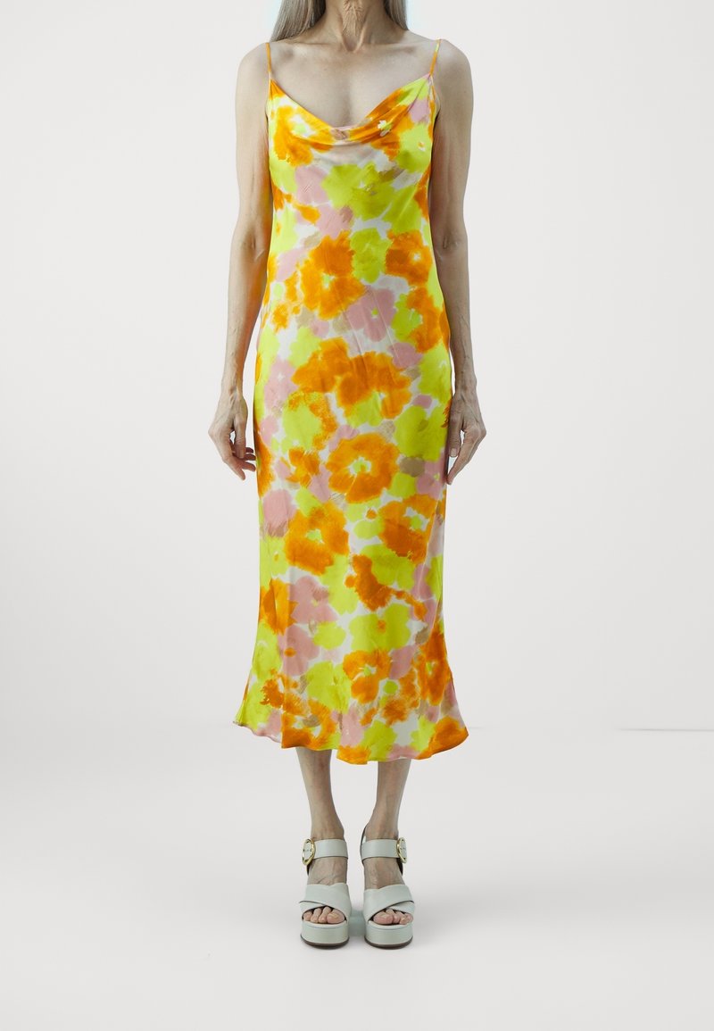 Robe sans manches à fleurs dans des teintes vives d'orange, de vert et de rose, fabriquée à partir d'un tissu léger et fluide ; elle présente un col bénitier.