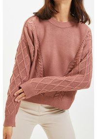 Gestrickter Pullover in Staubrosa, mit einem gerippten Rundhalsausschnitt und strukturierten Ärmeln mit Diamantmuster. Lockerer Schnitt mit verlängerten Bündchen.