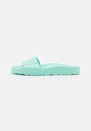 Sandale à glissière unique vert menthe avec semelle intérieure texturée et large bride, semelle inclinée pour une légère élévation du talon, sur fond blanc uni.