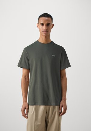 T-shirt in cotone verde scuro con scollatura rotonda e maniche corte. Presenta un piccolo logo ricamato sul petto sinistro.