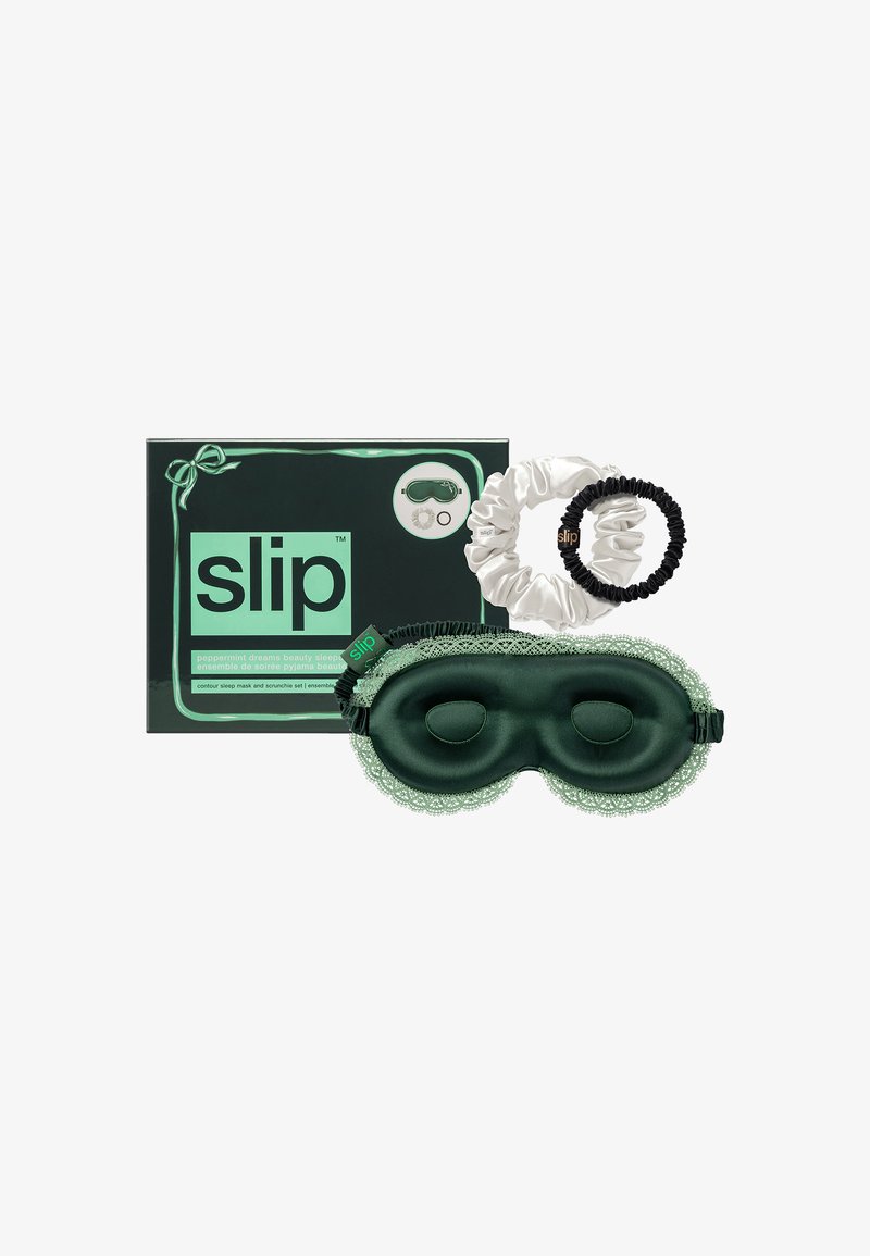 Groene zijden slaapmasker met kantafwerking, vergezeld van witte en zwarte zijden scrunchies, verpakt in een groene doos met het merkteken.