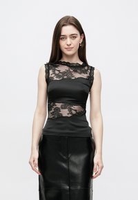 Juoda berankovė palaidinė su nėrinių sluoksniu, išraižytu iškirpte ir aptempta siluetu, derinama su juoda odine sijonu.