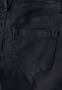 Jeans de mezclilla negra con un bolsillo trasero rectangular con costura superior y una textura suave. La tela parece duradera y bien confeccionada.