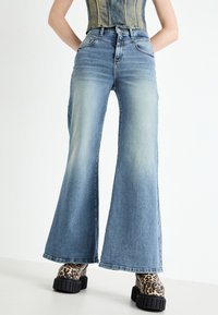 Light blue flared denim jeans with faded accents, a high waist, and five pockets, paired with chunky leopard print platform boots.